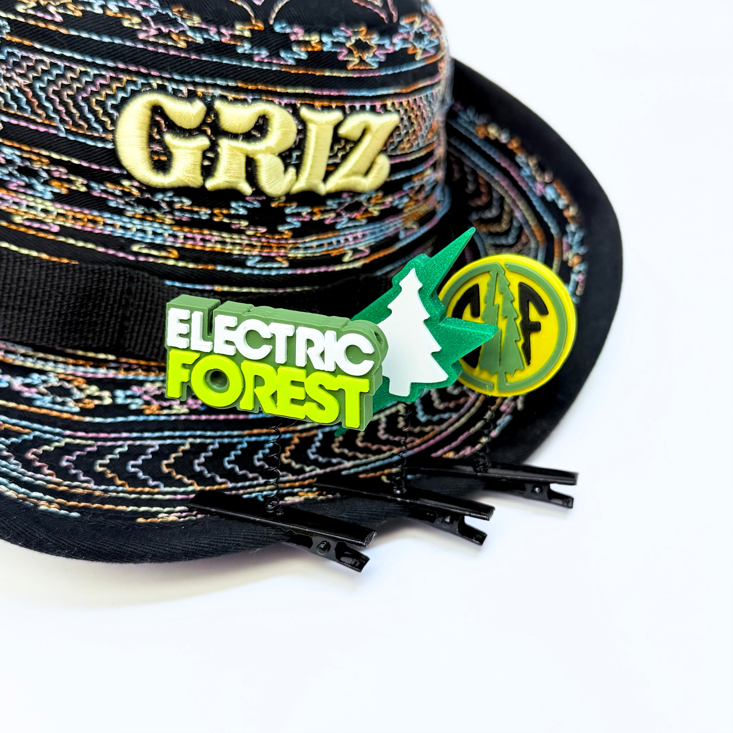 Electric Forest rave sprout set showing EF text rectangle and forest coin spring clip accessories on a GRiZ embroidered festival bucket hat with black fringe