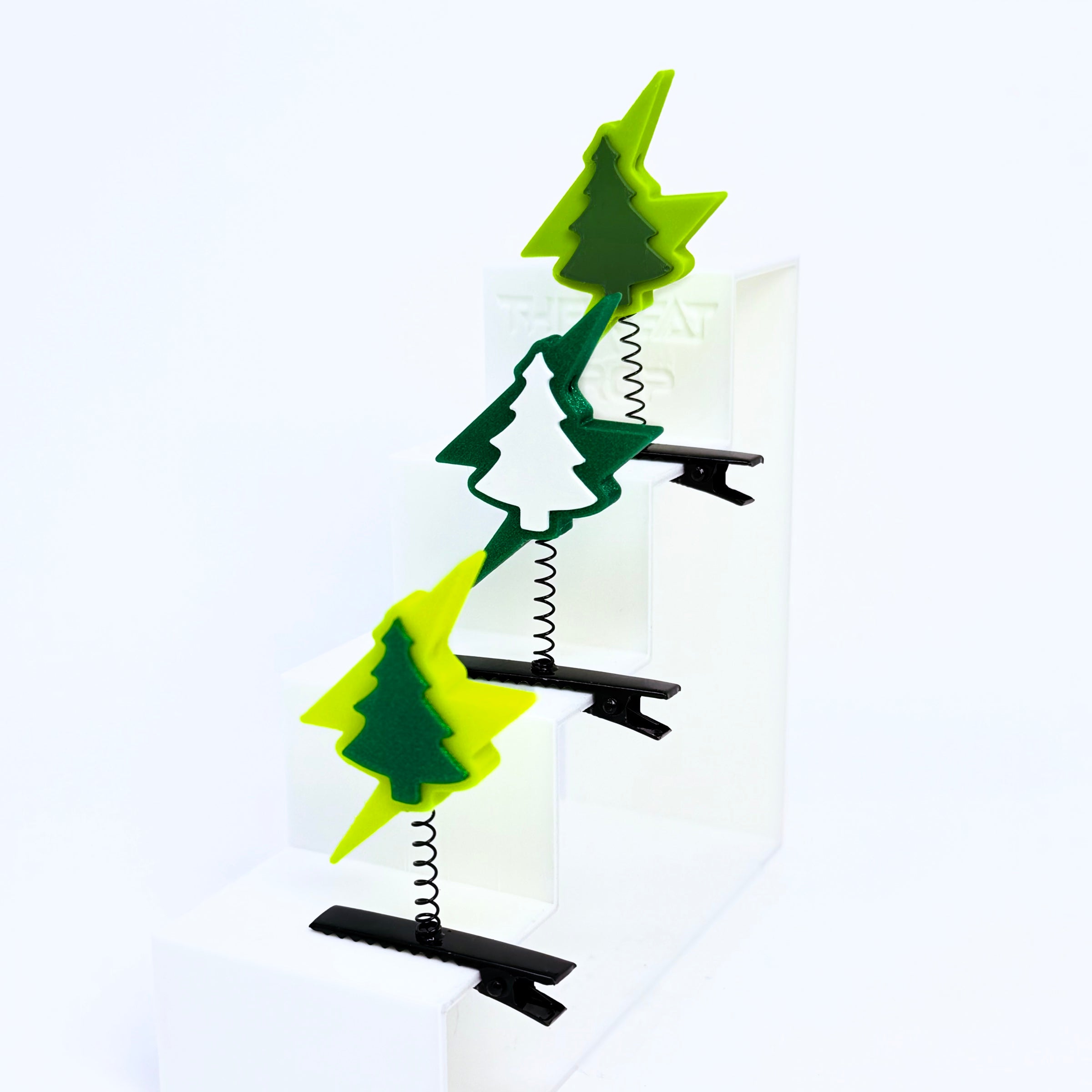 Three Electric Forest lightning bolt pine tree rave sprouts displayed on a white step riser in neon yellow/dark green, dark green/white, and yellow-green/forest green colorways