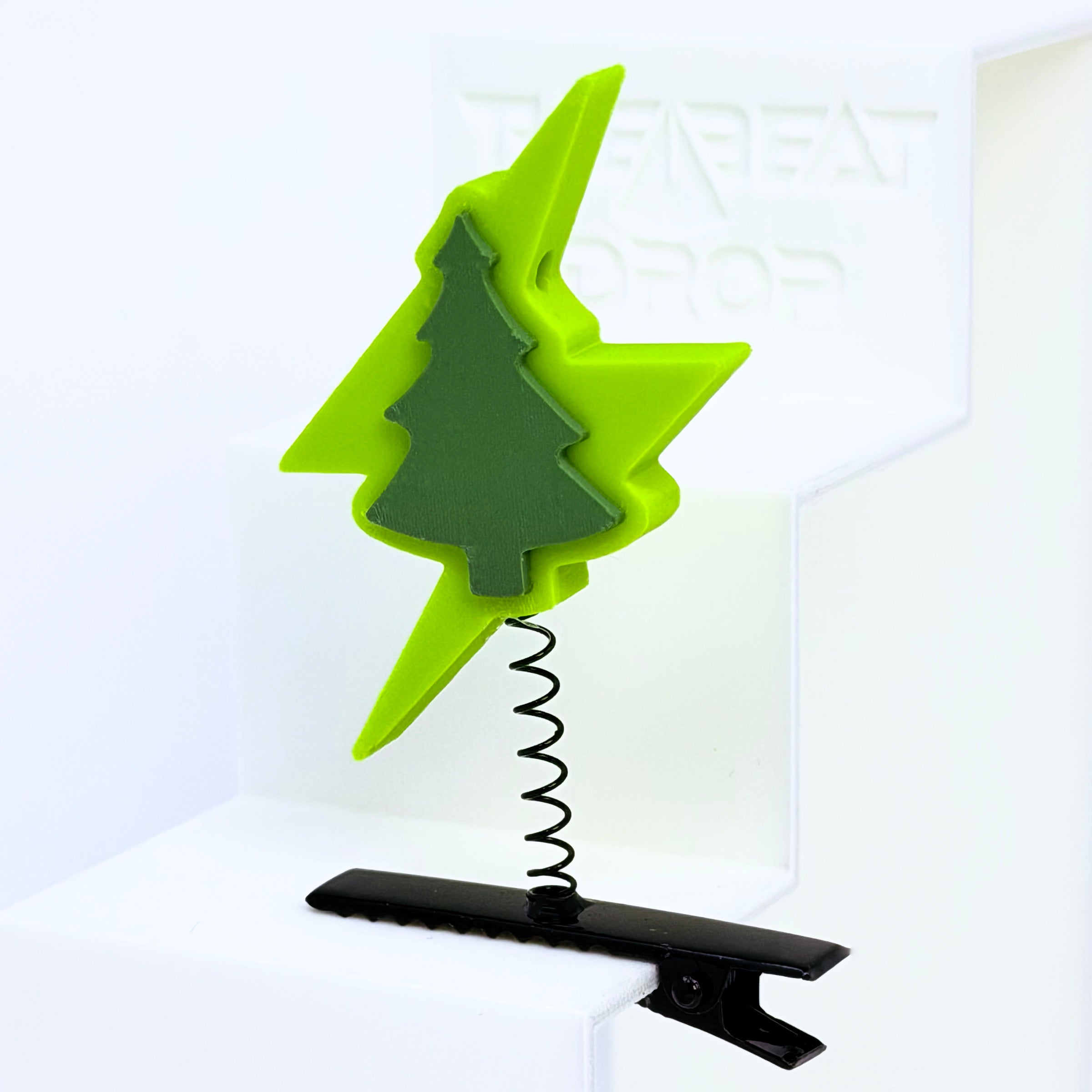 Close-up of Electric Forest lightning bolt rave sprout in neon yellow-green with dark sage pine tree, mounted on black metal spring hair clip