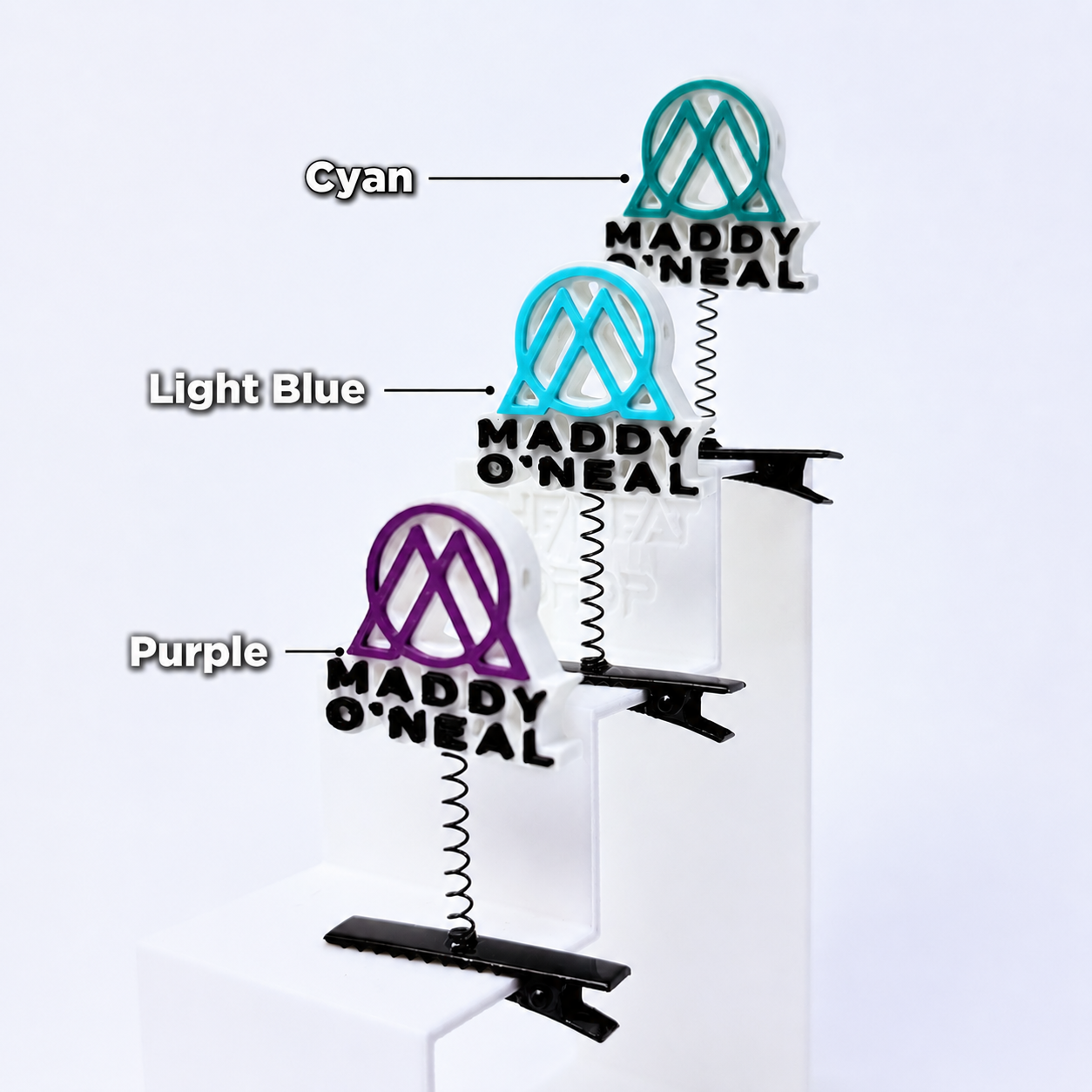 Maddy O'Neal rave sprout multi-color  with text by color — EDM festival hair clip accessory clipped to a white latter.